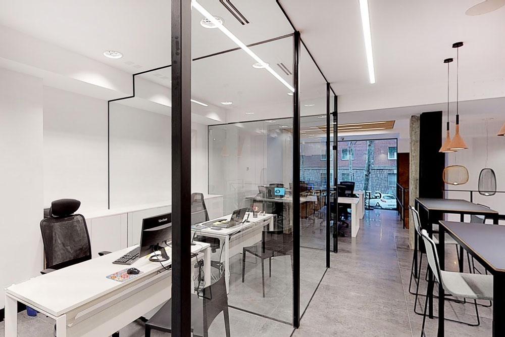 Despachos separados mediante mamparas transparentes en oficina de diseño moderno