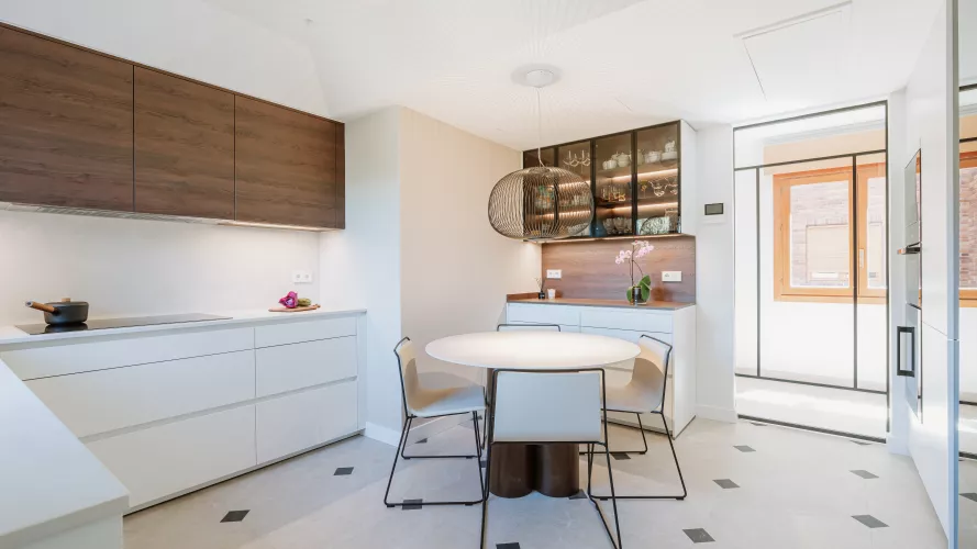 Cocina blanca con madera oscura y vitrinas iluminadas