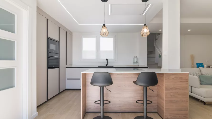 Cocina minimalista, abierta con isla central en tonos cálidos