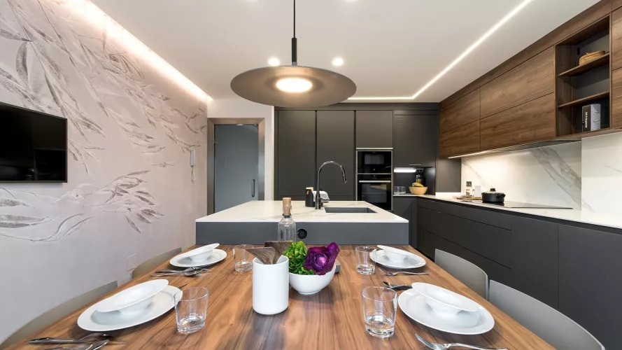 Cocina gris con isla, papel pintado Glamora y lámpara Foscarini