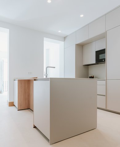 Cocina blanca con isla central y detalles en madera: amplitud, equilibrio y funcionalidad
