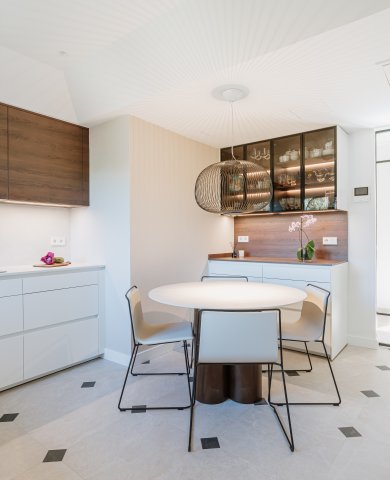 Cocina blanca con madera oscura y vitrinas iluminadas: equilibrio, calidez y funcionalidad