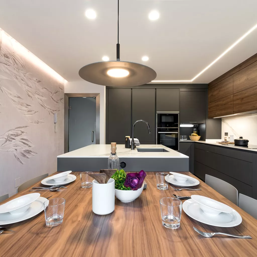 Cocina gris con isla, papel pintado Glamora y lámpara Foscarini